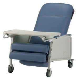 A medical recliner chair with blue cushioning, armrests, and a detachable wheeled tray. The chair is designed to enhance patient comfort and features wheels for easy mobility.