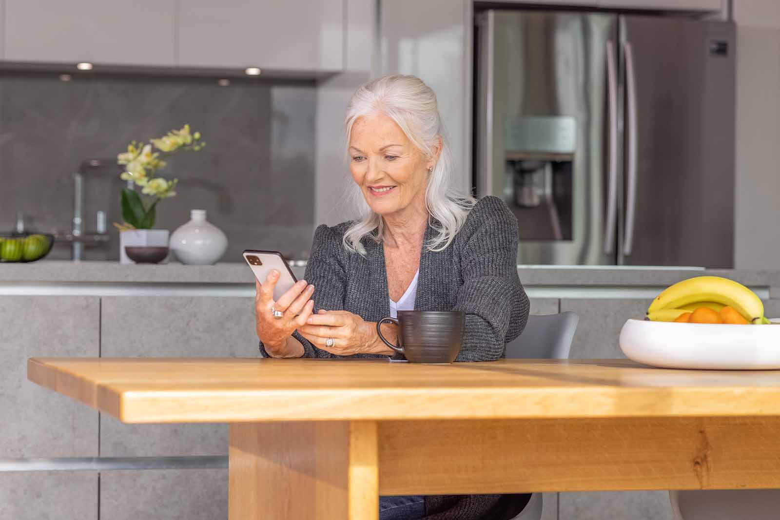 Woman in Kitchen, using Invacare support resource on phone